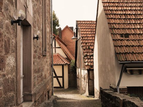 A narrow cobblestone lane between old low houses, evoking the village atmosphere of Böhmisches Dorf Rixdorf in Berlin-Neukölln.