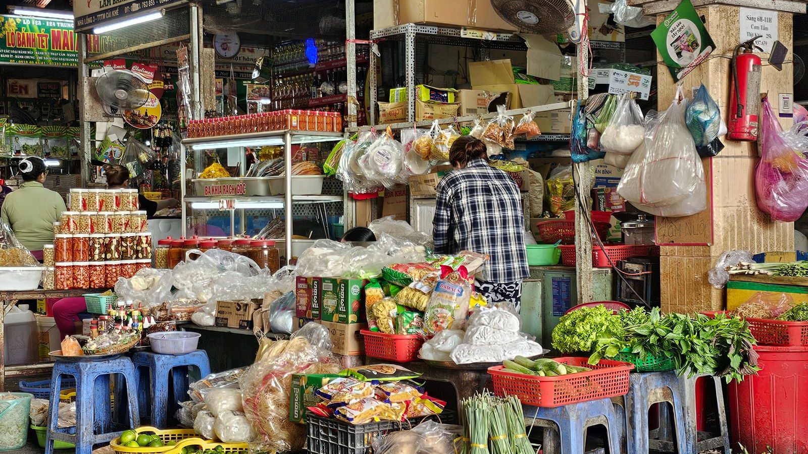 A busy Vietnamese market stall piled with fresh vegetables, herbs and goods, evoking the Dong Xuan Center's Asian wholesale halls in Berlin-Lichtenberg.