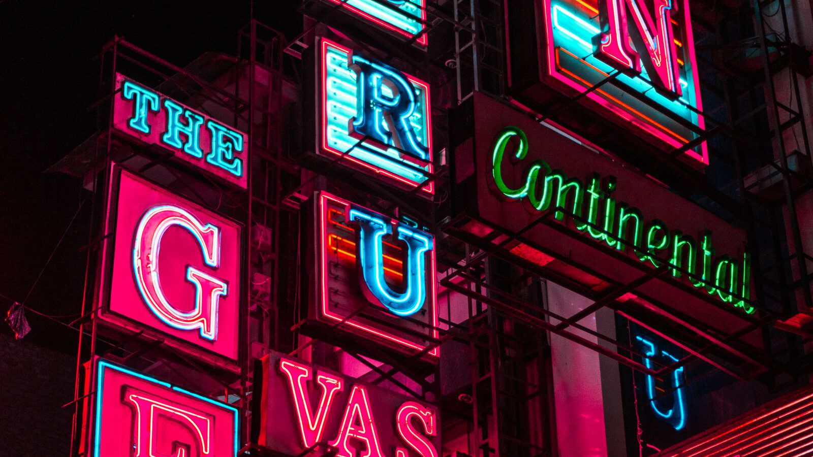 A dense stack of brightly coloured vintage neon signs glowing at night