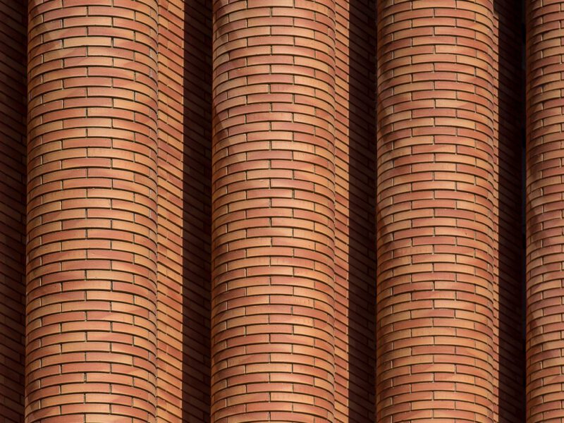 A close-up of curved, sculptural red-brick columns evoking the expressionist brickwork of the Amsterdam School.