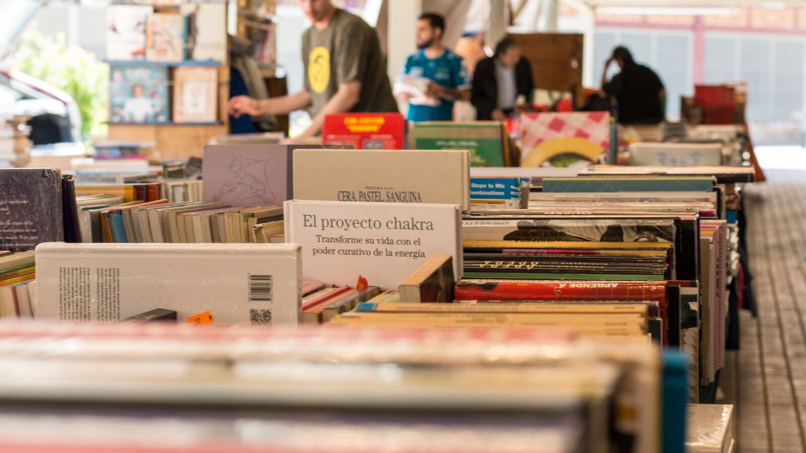 Rows of second-hand books on outdoor stalls at Barcelona's Sant Antoni Sunday book market, with browsers in the background.