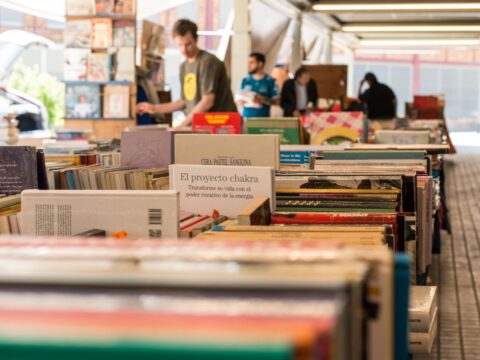 Rows of second-hand books on outdoor stalls at Barcelona's Sant Antoni Sunday book market, with browsers in the background.