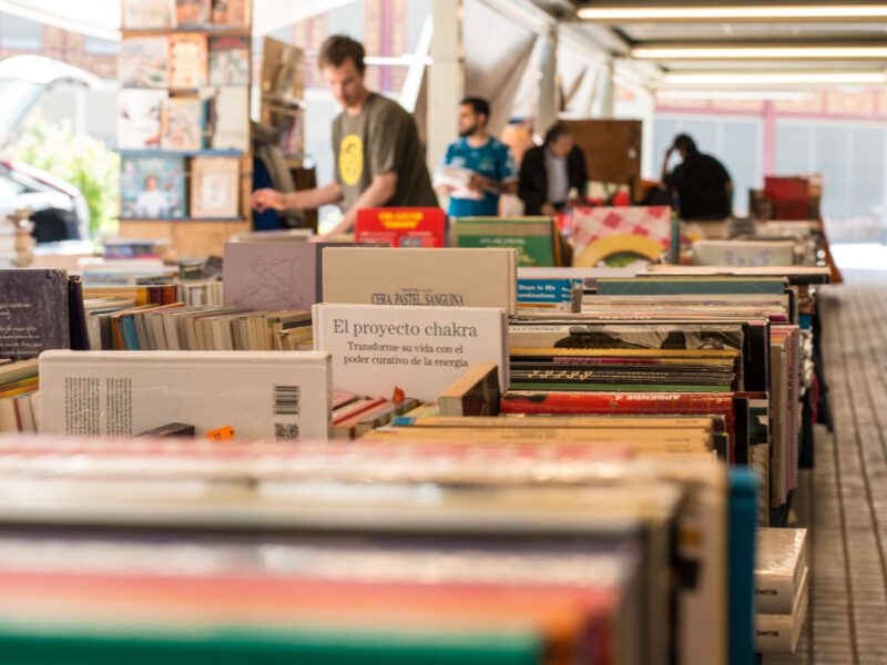 Rows of second-hand books on outdoor stalls at Barcelona's Sant Antoni Sunday book market, with browsers in the background.