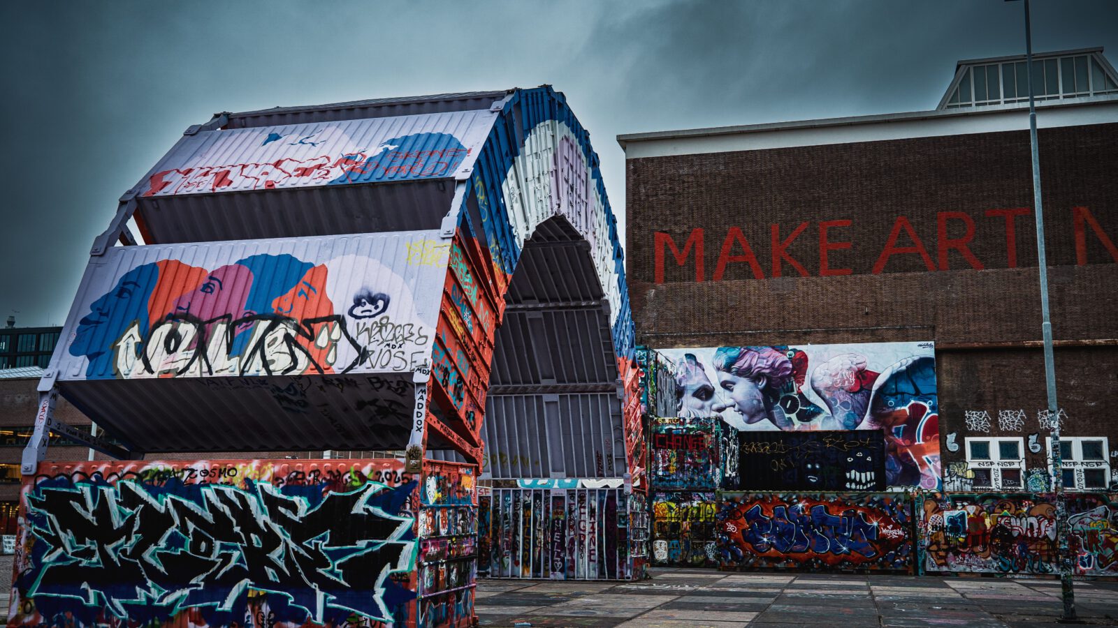 Colorful street art and graffiti adorn a warehouse exterior, creating a striking urban scene