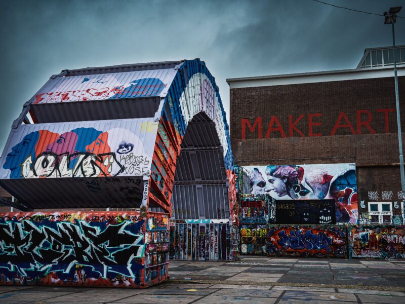 Colorful street art and graffiti adorn a warehouse exterior, creating a striking urban scene